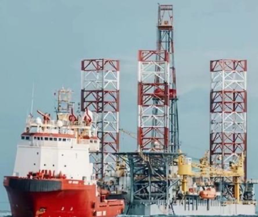Offshore jack-up drilling rig with support vessel